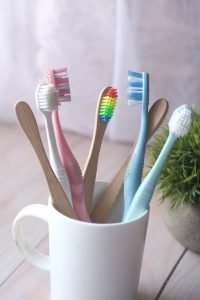 colorful toothbrushes in white mug against a wall